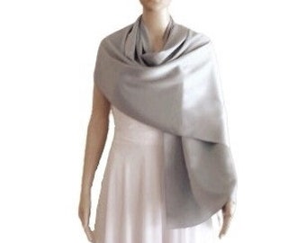 May include: A silver shawl made of soft fabric. The shawl is draped over a mannequin's shoulders and is flowing down the front of the mannequin.
