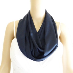 May include: A dark blue infinity scarf made of soft fabric. The scarf is draped around a mannequin's neck.