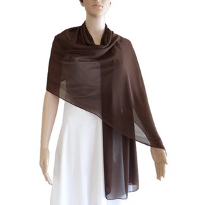 May include: A brown chiffon shawl draped over a white dress. The shawl is sheer and lightweight, making it a perfect accessory for a wedding or other special occasion.