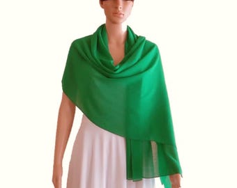 May include: A vibrant green shawl draped over a mannequin. The shawl is made of a lightweight fabric and is a solid, bright green color. The mannequin is wearing a white dress, creating a contrast with the shawl.