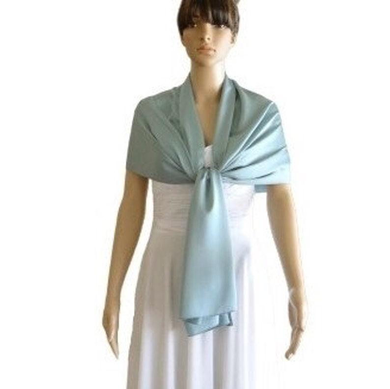 May include: A light blue satin shawl, draped over a white dress form. The shawl is tied in a knot at the neck.