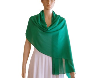 May include: A bright green chiffon shawl draped over a white dress. The shawl is lightweight and sheer, making it perfect for a special occasion.