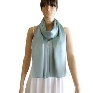 May include: A light blue satin scarf. The scarf is long and thin, and it is draped around a mannequin's neck.