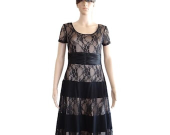 May include: A black lace dress with a black satin sash and a layered skirt. The dress has a scoop neckline and short sleeves.