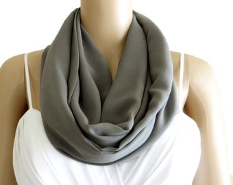 May include: A gray infinity scarf made of soft fabric. The scarf is draped around a mannequin's neck.
