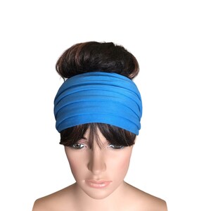 May include: A bright blue headband made of soft fabric. The headband is folded and worn around the head, covering the forehead and ears.