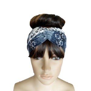May include: A blue and white floral patterned headband with a twisted knot design. The headband is worn on a mannequin with brown hair.