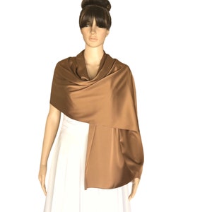 Puede incluir: Un chal de satén marrón drapeado sobre un maniquí blanco. El chal es un diseño simple y elegante que sería una gran adición a cualquier armario.