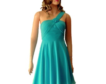 May include: A turquoise one-shoulder dress with a ruffled bodice and a flower accent. The dress has a flared skirt and is made of a lightweight fabric.