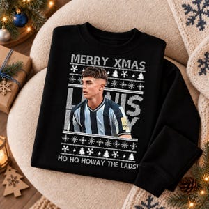 May include: A black long-sleeve sweatshirt featuring a graphic print of a person in a black and white striped jersey. The design includes the text MERRY XMAS and HO HO HOWAY THE LADS, surrounded by white snowflake and Christmas tree patterns.