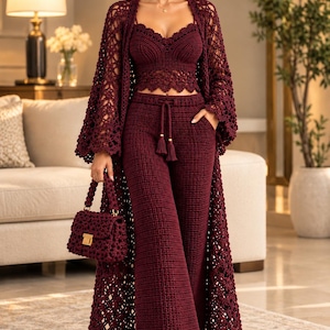 May include: A deep burgundy crochet three-piece set consisting of a sleeveless crop top with a scalloped hem, wide-leg trousers with a drawstring waist, and a long, open-front duster cardigan with wide sleeves, paired with a matching handbag.