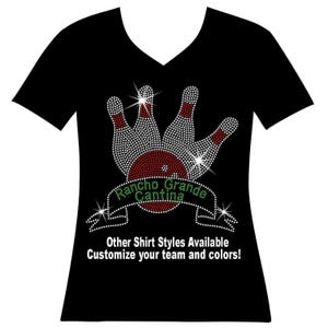 May include: A black V-neck t-shirt featuring a rhinestone graphic of three bowling pins and a bowling ball. A banner across the center displays the text Rancho Grande Cantina in green rhinestones. Below the graphic, white text reads Other Shirt Styles Available Customize your team and colors!