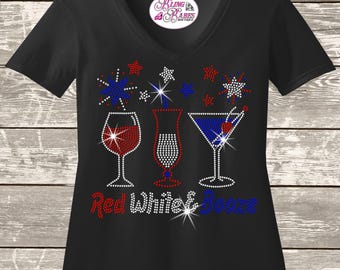 Könnte beinhalten: Ein schwarzes T-Shirt mit V-Ausschnitt und einem Strass-Motiv aus drei Cocktailgläsern in Rot, Weiß und Blau. Über den Gläsern befinden sich Sterne und darunter der Text Red White & Booze. Das Markenlogo Bling Babes Boutique befindet sich am Hals.