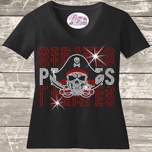 May include: Black V-neck t-shirt with a rhinestone pirate skull design. The design includes a pirate hat, skull, and the word "PIRATES" in red and white rhinestones. The shirt also has the text "Bling Babes Boutique".