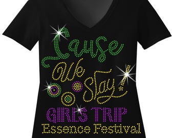 May include: Black v-neck t-shirt with a rhinestone design that reads "Cause we stay! Girls Trip Essence Festival".