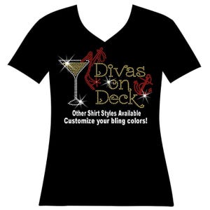 May include: A black V-neck t-shirt featuring a rhinestone graphic of a martini glass and an anchor with the text "Divas on Deck" in gold and red crystals. Below the graphic, white text reads "Other Shirt Styles Available Customize your bling colors!"