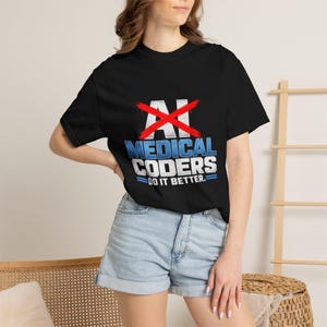 Puede incluir: Una camiseta negra de manga corta con un gráfico que muestra el texto AI tachado en rojo, seguido del texto en azul y blanco MEDICAL CODERS DO IT BETTER. El diseño incluye dos líneas horizontales azules debajo de la última línea de texto.