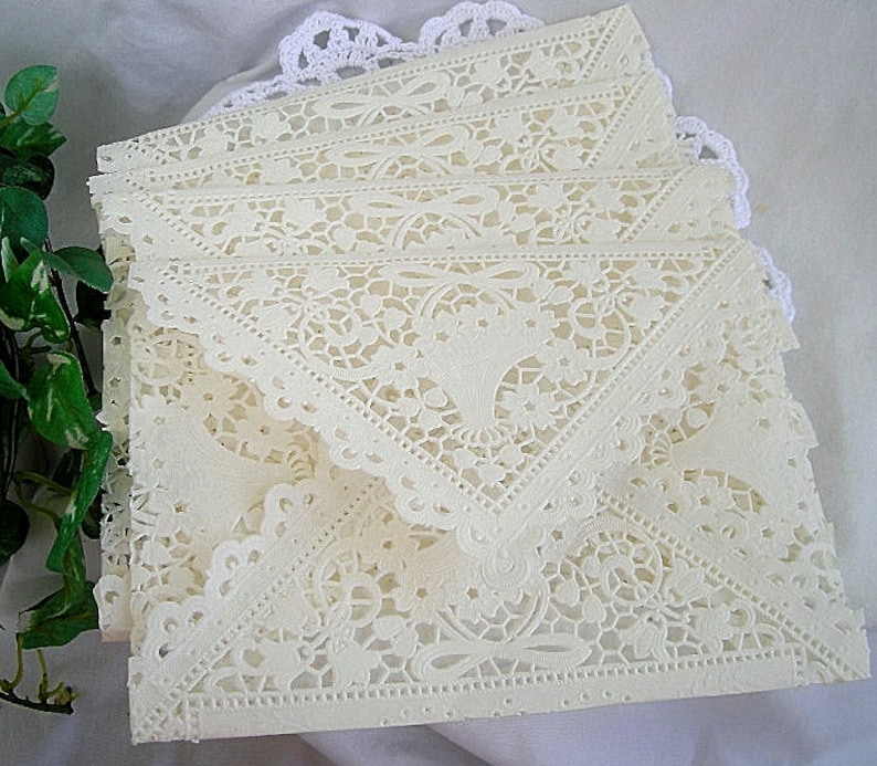 May include: A stack of ivory lace paper envelopes with a delicate floral pattern. The envelopes are folded and ready to be used for special occasions.