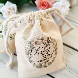 May include: A small white cotton drawstring bag with a green floral design and the text "The Perfect Blend John & Sally 1/15/24".