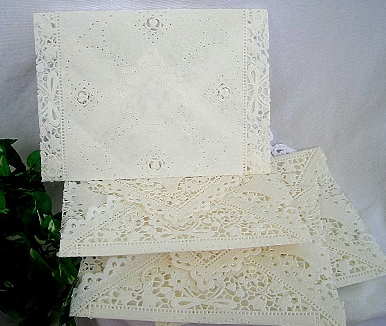 May include: A stack of four white doilies with intricate lace patterns. The doilies are made of delicate paper and have a vintage look.