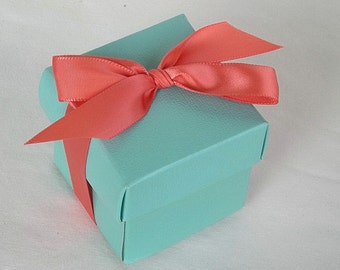 May include: A small, turquoise blue gift box with a coral satin ribbon tied in a bow on top.