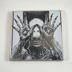 May include: A square ceramic tile featuring a black and white ink-style illustration of a creature with long, clawed fingers held up to its face. The creature has an eye embedded in the palm of each hand and a pale, featureless face.