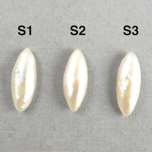 May include: Three elongated, off-white pearls are displayed against a gray background. Each pearl is labeled with a black capital "S" followed by a number. The pearls have a pearlescent sheen, reflecting light.