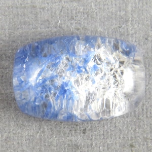 May include: A rectangular, translucent gemstone with a mix of blue and white internal structures. The stone has rounded edges and a polished appearance, set against a neutral gray background.
