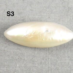 May include: A lustrous, off-white, elongated pearl with a smooth surface. The pearl has a subtle, iridescent sheen and a slightly irregular shape. The text "S3" is visible in the upper left corner.