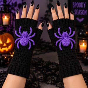 May include: A pair of black fingerless gloves made of crocheted yarn. Each glove features a prominent, three-dimensional purple spider appliqué centered on the back of the hand. The gloves have a ribbed cuff at the wrist and an open finger design.