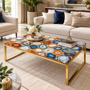 Peut inclure: Une table basse rectangulaire dotée d'un plateau composé de nombreuses tranches d'agate polies et multicolores dans des tons de bleu, d'orange et de blanc, encadrées par une base en métal doré aux lignes droites et épurées.