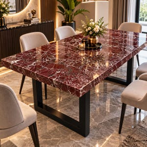 May include: A rectangular dining table with a polished deep red marble top featuring white veining, supported by a black metal U-shaped frame. The table is surrounded by four light beige upholstered chairs with dark wooden legs.