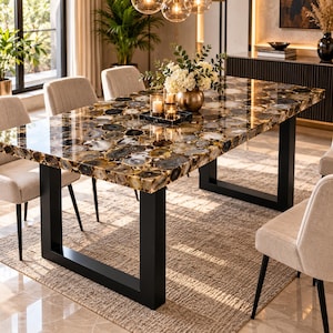 May include: A rectangular dining table featuring a polished surface composed of numerous circular, multi-toned brown, black, and white agate slices. The tabletop is supported by a sturdy, matte black metal frame with two U-shaped legs.