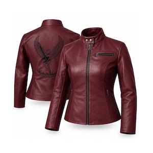 May include: A burgundy leather jacket featuring a stand-up collar with two snap buttons, a front zip closure, and zipped pockets. The back displays an embroidered graphic of a winged figure with the text Made In Heaven below it.