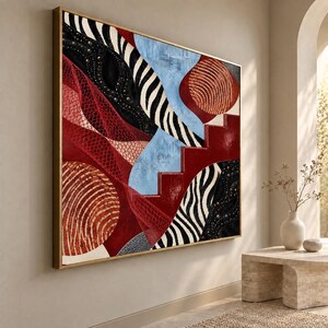 May include: A large rectangular wall art piece in a gold frame featuring an abstract composition of red, black, white, and light blue shapes. The design includes zebra-like stripes, circular patterns, a red staircase motif, and textured black areas.