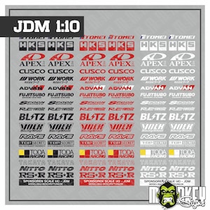 Peut inclure: Une planche de décalcomanies présentant des logos de marques automobiles JDM à l'échelle 1:10 en noir, rouge et blanc. La planche comprend plusieurs rangées de noms de marques tels que HKS, APEXi, CUSCO, WORK, ADVAN, FUJITSUBO, SPOON, RE-AMEMIYA, BLITZ, VOLK, RAYS, TOP SECRET, TODA, TAKATA, NITTO et RS*R.