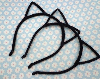 May include: Three black fuzzy cat ear headbands. The headbands are made of a soft, flexible material and have a simple design.