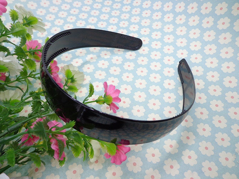 May include: A black plastic headband with a textured surface. The headband is curved and has a smooth, glossy finish.
