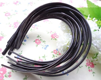 May include: A set of black plastic headbands with a textured edge. The headbands are stacked on top of each other.