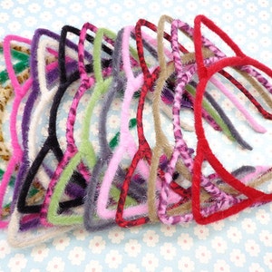 May include: A set of 12 cat ear headbands in various colors and patterns, including leopard print, pink, green, purple, and red. The headbands are made of soft, fuzzy material and are perfect for adding a playful touch to any outfit.