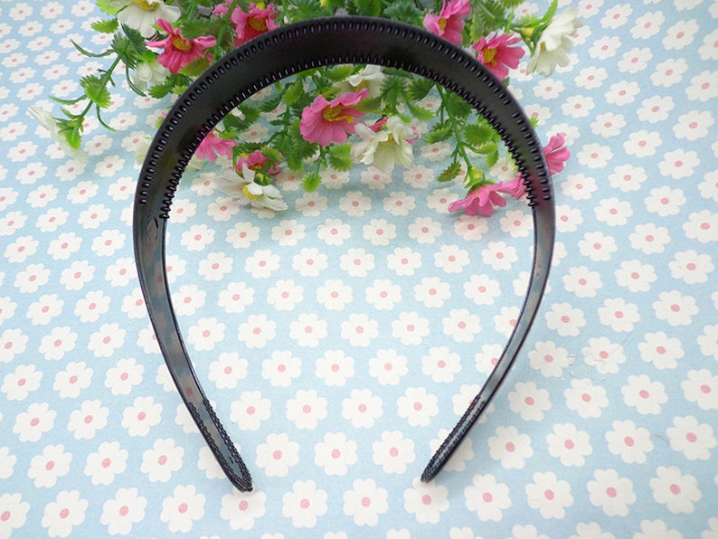 May include: A black plastic headband with a textured surface. The headband is designed to hold hair in place.