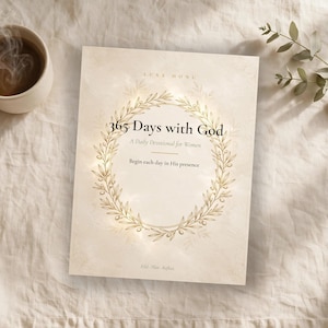 以下が含まれることがあります： 365 Days with God, A Daily Devotional for Womenというタイトルのデボーションブック。クリーム色の表紙に金のオリーブの枝のリースが描かれており、Luxe HonuおよびBegin each day in His presenceというテキストが記されています。