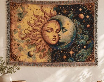 Könnte beinhalten: Ein rechteckiger Webteppich mit Sonne und Mond mit menschlichen Gesichtern. Die linke Seite zeigt eine goldene Sonne mit strahlenden Flammen, während die rechte Seite einen blauen Halbmond vor einem dunklen Sternenhimmel mit Planeten zeigt.