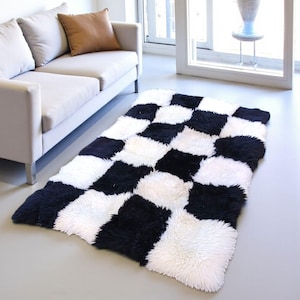 Puede incluir: Una alfombra rectangular con una textura de pelo largo y tupido, dispuesta en un llamativo patrón de tablero de ajedrez alternado con cuadrados negros y blancos sólidos. La alfombra se extiende sobre el suelo con fibras densas y suaves.