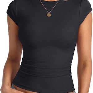 Peut inclure: Un t-shirt noir à manches courtes avec une texture côtelée, une encolure ronde et une coupe ajustée. Le t-shirt présente un design simple avec une couleur noire unie sur l'ensemble, offrant un aspect épuré et polyvalent pour diverses tenues.