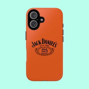 Può includere: Una custodia per smartphone arancione con il logo nero Jack Daniel's Old No. 7 Brand stampato al centro. La custodia presenta un modulo fotocamera nero nell'angolo in alto a sinistra con due lenti circolari e un piccolo flash visibile.