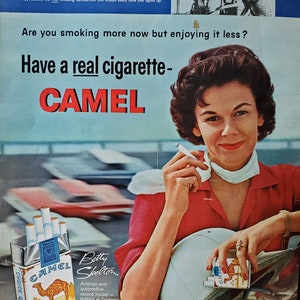 Peut inclure: Une publicité vintage pour les cigarettes Camel mettant en scène une femme en chemise rouge et en foulard blanc tenant un paquet de cigarettes Camel. Le texte de la publicité dit "Have a real cigarette - CAMEL" et "The best tobacco makes the best smoke!"