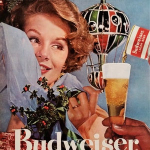 May include: Vintage advertisement for Budweiser beer. A woman smiles, holding a sprig of holly and a light blue fabric. A hand offers a glass of beer. The Budweiser logo is prominently displayed.