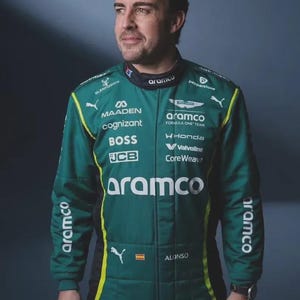 May include: A dark green racing suit featuring the text Aramco, Aston Martin, Cognizant, Boss, JCB, Maaden, Honda, Valvoline, and CoreWeave. The suit includes a Puma logo, a small Spanish flag, and the name Alonso printed on the chest area.