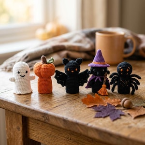 Peut inclure: Un ensemble de cinq petites figurines au crochet comprenant un fantôme blanc, une citrouille orange, une chauve-souris noire, une sorcière noire avec un chapeau violet et un balai, et une araignée noire. Chaque figurine présente des détails cousus.